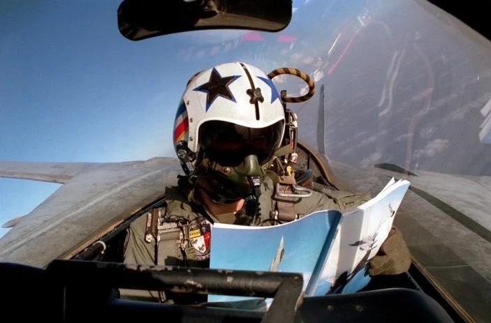Fighter pilot in a cockpit consulting a flight manual